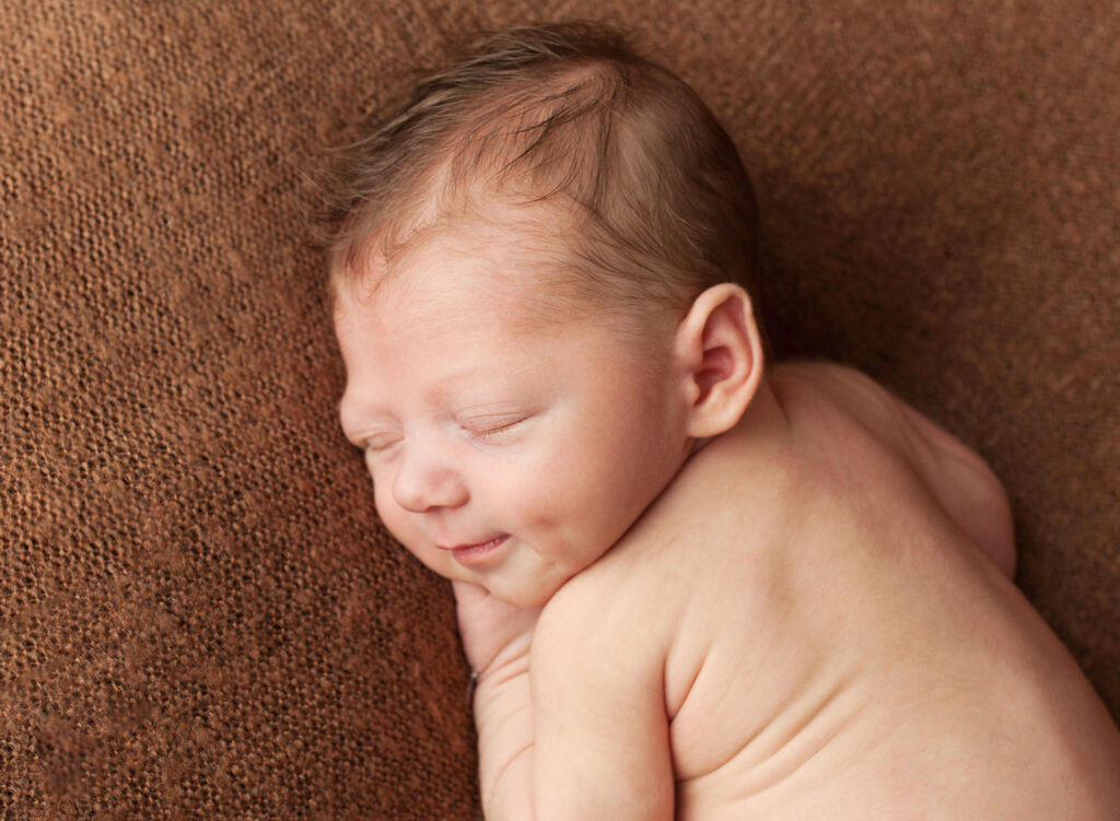 Sleeping newborn boy, smiling with dimples photography
