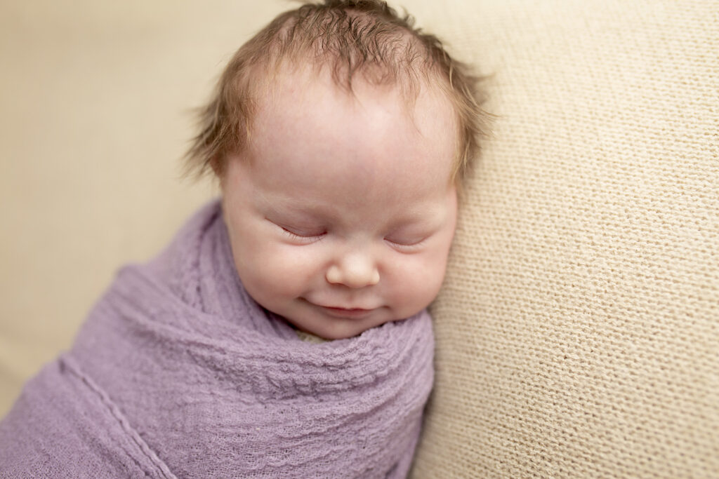 Smiling swaddled baby during professional newborn session